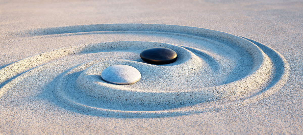 Steine im Sand als Yin Yang Symbol